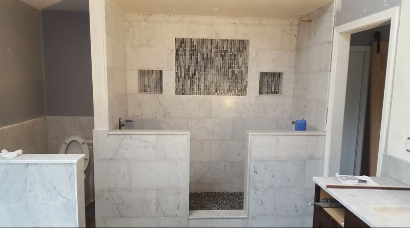 Luxurious marble walk-in shower with intricate tile work and built-in niches.