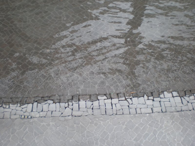 Close-up view of a tiled surface partially submerged in water, showcasing detailed stonework.