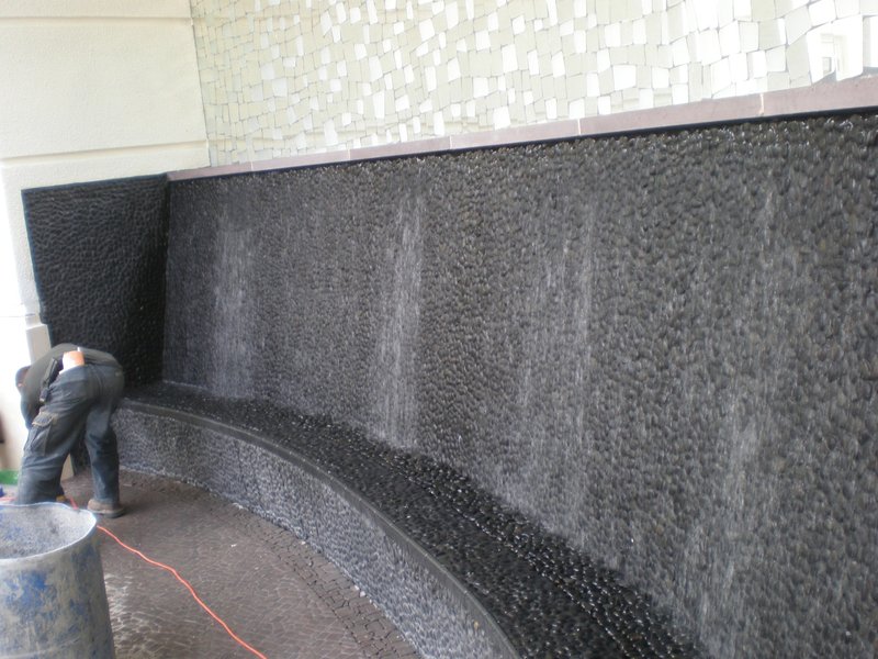 Tiled wall with water cascading down during the construction of a water feature.